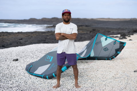 Duotone boardshorts en anthracite foncé debout sur plage volcanique rocheuse