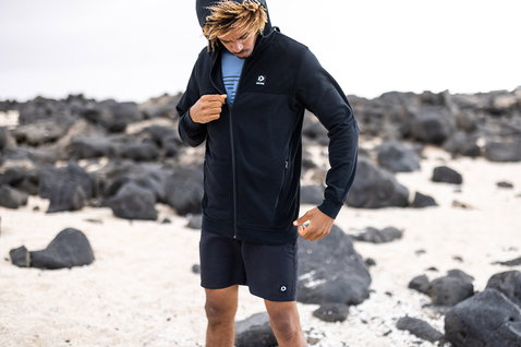 Duotone Apparel Reißverschluss-Hoodie in schwarzblau beim Posieren an einem Vulkanstrand