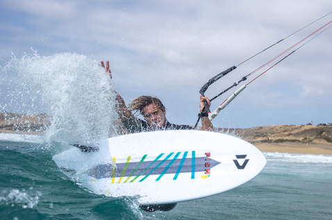 Duotone Fish D/LAB strapless surfboard during kitesurfing at the ocean beach with sandy dunes