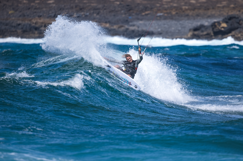 Duotone Fish D/LAB directional kiteboard during wave riding at rocky ocean coastline