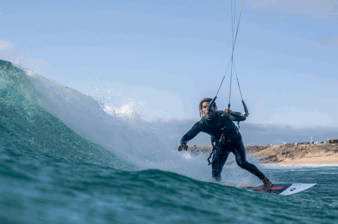 Duotone Wam D/LAB wave kiteboard durante surf de olas en la playa del océano