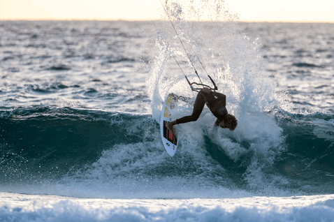 Duotone Wam D/LAB wave kiteboard durante el surf de olas en la playa del océano