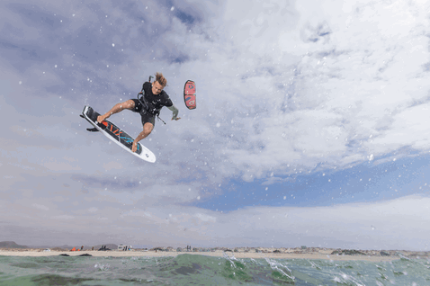 Duotone Neo SLS LEI kite durante el kitesurf en la playa del océano en gris acero, naranja y blanco