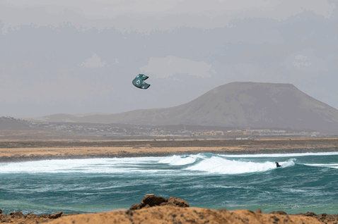 Duotone Neo SLS LEI kite durante el surf de olas en una playa con costa volcánica