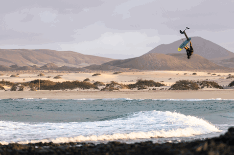 Duotone Pace SLS foil kiteboard en train de faire du foiling sur une plage côtière aride avec des dunes