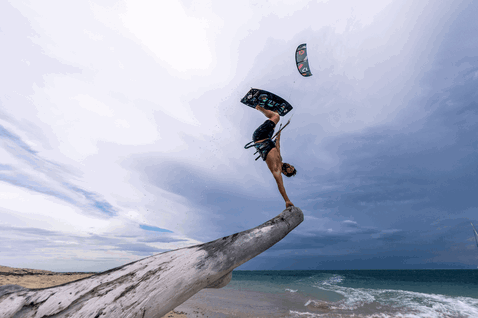 Duotone Rebel SLS LEI kite during kitesurfing at the ocean beach with driftwood in slate blue-grey, steel blue and light grey
