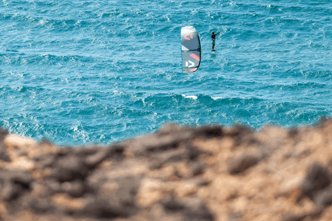 Duotone Rebel SLS LEI kite during kitesurfing at the ocean coast with rocky foreground