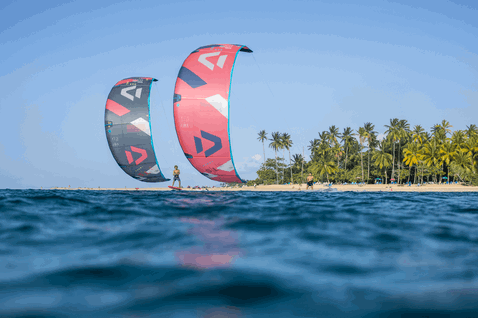 Duotone Rebel SLS LEI kite during kitesurfing at a tropical ocean beach with palm trees