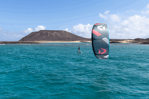 Duotone Rebel SLS LEI kite during kitesurfing at the ocean beach with volcanic island backdrop