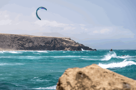 Duotone Whip SLS kite surfboard durante il kitesurf su un promontorio costiero roccioso