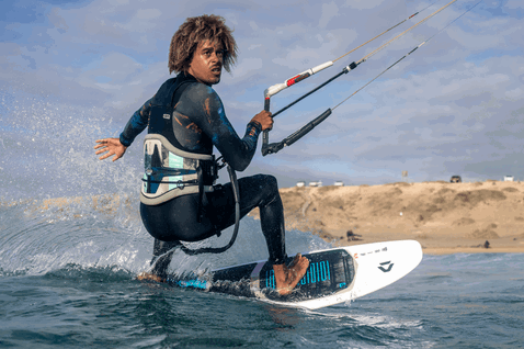 Duotone Whip SLS kite surfboard durante il kitesurf su spiaggia oceanica con dune di sabbia