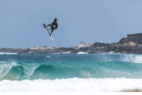 Duotone Whip SLS kite surfboard durante il kitesurf su costa oceanica con promontorio roccioso