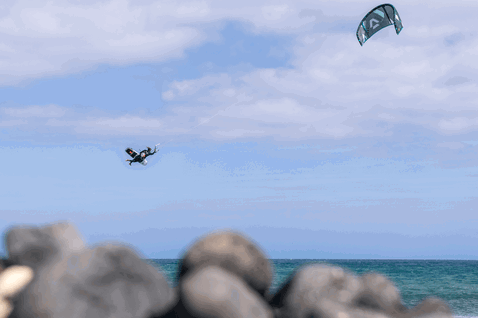 Tabla de kitesurf Duotone Voke SLS durante kitesurf en costa oceánica con rompeolas rocoso