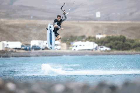 Duotone Voke SLS strapless freestyle kiteboard durante el kitesurf en laguna costera con colinas áridas
