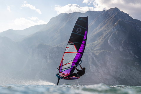 Duotone Warp_Foil 20.22 voile foil en wing foiling sur un lac de montagne en bleu marine foncé avec violet, cyan et rouge