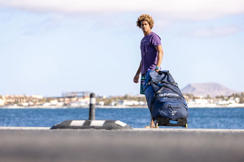 Duotone Kiteboarding Combibag 2024 kite bag while traveling at a coastal harbor