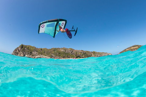 Duotone Slick Foil Wing beim Wing Foiling über türkisfarbenem Wasser mit Insel im Hintergrund