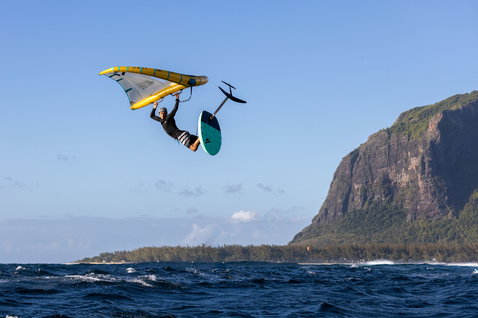 Duotone Unit D/LAB foil wing durante il wing foiling sopra l'oceano vicino a una costa tropicale