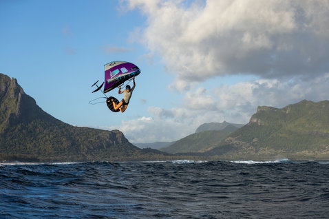 Duotone Unit foil wing durante il wing foiling in volo sull'oceano a Mauritius con montagne sullo sfondo