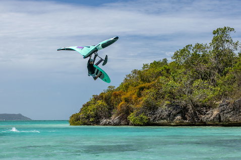 Duotone Unit ala da foil durante il wing foiling su acqua turchese vicino a un'isola tropicale in turchese e viola