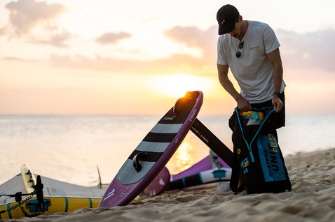 Duotone Unit D/LAB foil wing 6.0m nella borsa durante la preparazione al wing foiling sulla spiaggia al tramonto