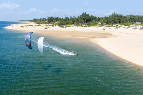 Duotone Evo LEI kite durante il kitesurf in una laguna costiera con spiaggia sabbiosa e vegetazione tropicale