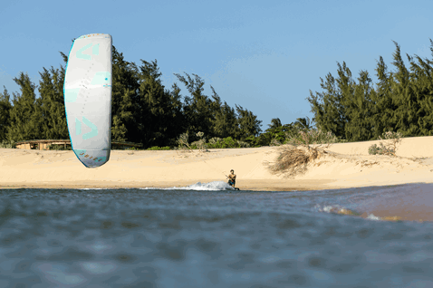 Duotone Juice LEI kite durante il kitesurf in una laguna tropicale con riva sabbiosa e pini