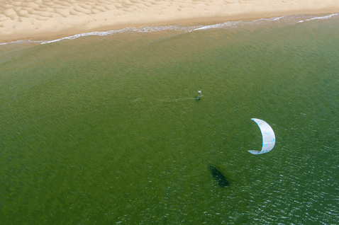Duotone Juice LEI kite durante il kitesurf in acque costiere poco profonde con spiaggia sabbiosa