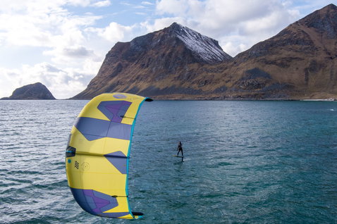 Duotone Dice SLS LEI kite during foiling in an ocean bay with mountain backdrop
