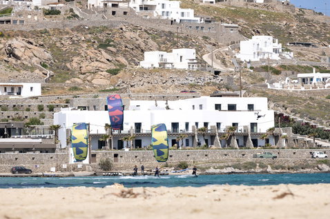 Duotone Dice SLS LEI kite during kitesurfing at a Mediterranean sandy beach with white buildings on rocky hillside
