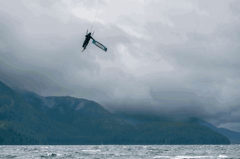 Duotone Rebel SLS kite LEI durante il kitesurf su un lago di montagna con sfondo boschivo