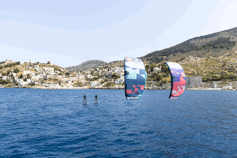 Aquilone LEI Duotone Neo SLS durante il wing foiling in una baia con villaggio costiero mediterraneo