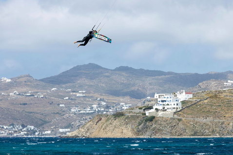 Duotone Jaime twin-tip kiteboard during kitesurfing at ocean coastline with Mediterranean village backdrop