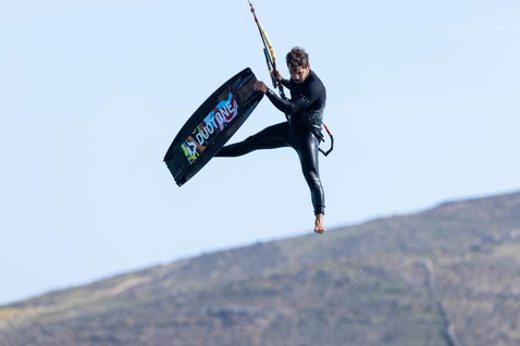 Duotone Jaime SLS twin-tip kiteboard during kitesurfing at a coastal location with mountainous backdrop