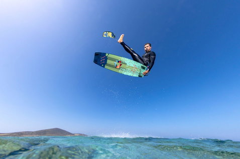 Tavola da kitesurf twin-tip Duotone Select durante il kitesurf sulla costa oceanica con acqua turchese