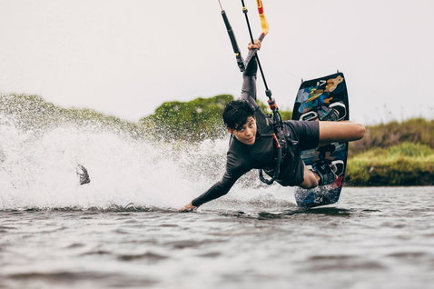 Kiteboard twin-tip Duotone Soleil SLS lors du kitesurf dans un lagon côtier avec végétation verte