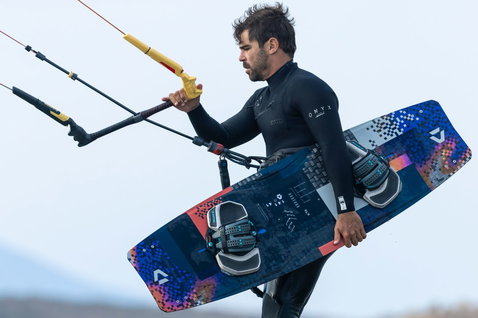 Duotone Select SLS twin-tip kiteboard during kitesurfing at a beach with overcast sky