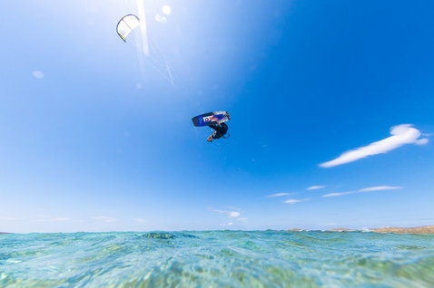 Duotone Select SLS twin-tip kiteboard during kitesurfing in the open ocean with coastline in the background