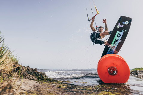 Duotone Team Series SLS twin-tip kiteboard during kitesurfing at a coastal lagoon with sandy shore