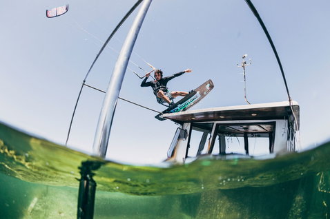 Duotone Team Series SLS twin-tip kiteboard during kitesurfing over a boat deck in the ocean off Sardinia