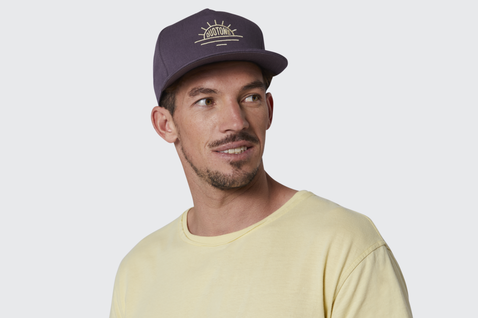 Duotone Snapback Cap in dunkel marineviolett mit gold-gelber Stickerei, getragen im Studio