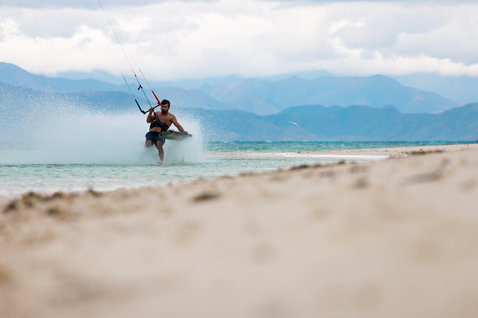 Duotone Evo SLS LEI Kite beim Kitesurfen am Meer mit Bergkulisse