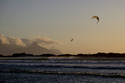 Duotone Evo SLS LEI Kite beim Kitesurfen an einem Strand mit Bergkulisse
