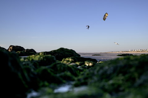Duotone Evo SLS LEI Kite beim Kitesurfen am Ozeanstrand mit felsigem Vordergrund