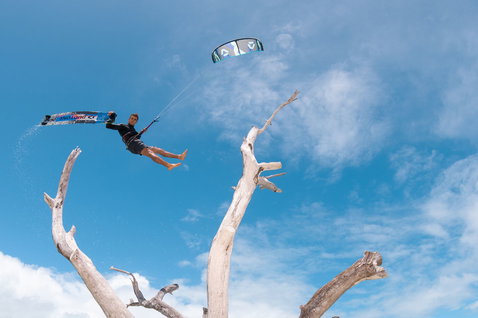 Duotone Evo SLS LEI Kite beim Kitesurfen an einem tropischen Strand mit Treibholzbäumen