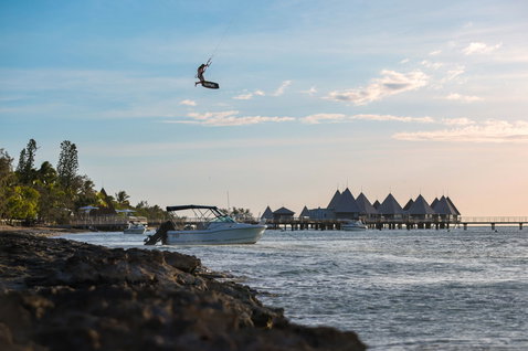 Duotone Evo D/LAB LEI kite during kitesurfing at a tropical coastal lagoon with overwater bungalows in New Caledonia
