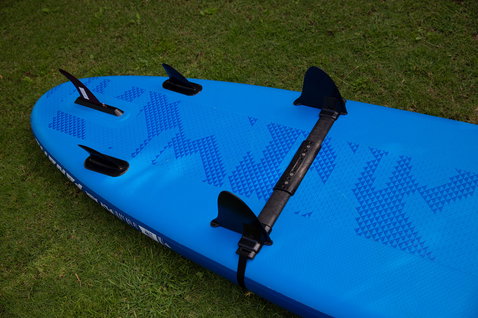 Aileron additionnel Duotone Windsurfing Add-On Drift Stopper monté sur un SUP sur une pelouse extérieure