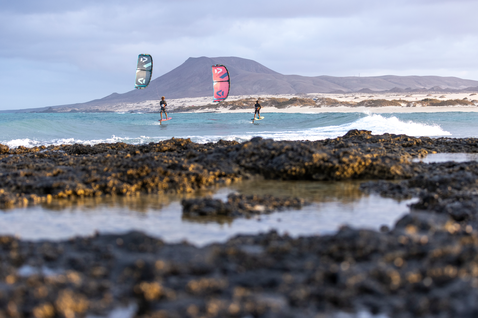 Duotone Foil Set Complete AL Surf set foil kitesurf durante il foiling su spiaggia oceanica con costa rocciosa vulcanica