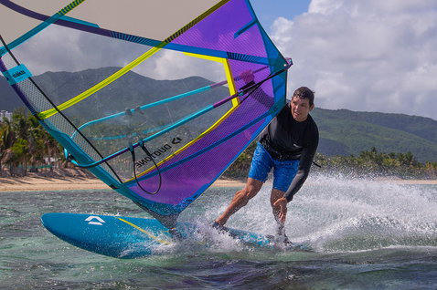 Duotone FreeWave SLS windsurf board during wave riding at a tropical beach in shallow turquoise water