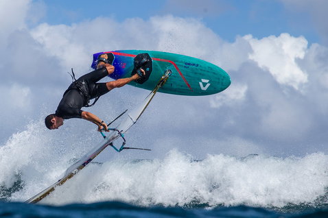 Duotone Grip 3 SLS planche de windsurf lors du surf de vagues dans l'océan en sarcelle avec rouge et violet
